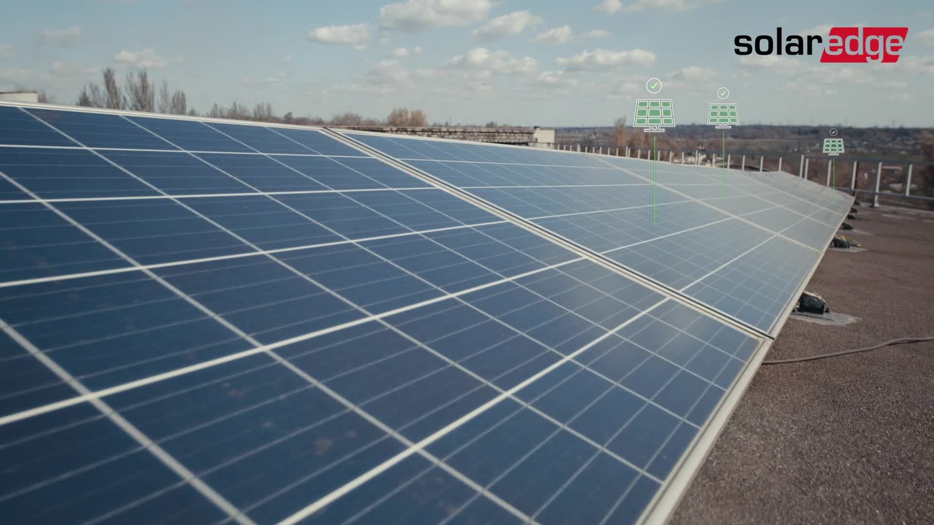 Row of solar panels on a rooftop with a clear sky and distant landscape.